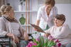 a care worker showing two elderly women her clipboard